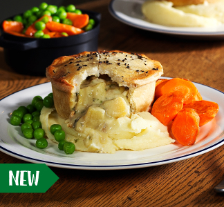 Brewers Fayre vegan pie on a plate with green peas and carrots with a fork.